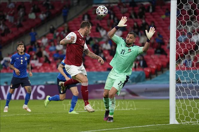 Trong ảnh: Tiền đạo Áo Marko Arnautovic (trái) đánh đầu chạm xà ngang dội vào khiến lưới của thủ môn Italy Gianluigi Donnarumma lần đầu tiên bị chọc thủng. Tuy nhiên, bàn thắng sau đó không được công nhận do lỗi việt vị, trong trận đấu vòng 16 đội, vòng chung kết EURO 2020 ở Wembley (Anh) ngày 26/6/2021. Ảnh: AFP/TTXVN