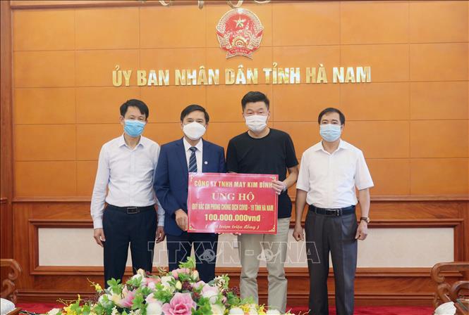 Trong ảnh: Tiếp nhận ủng hộ 100 triệu đồng từ Công ty TNHH may Kim Bình. Ảnh: Nguyễn Chinh - TTXVN