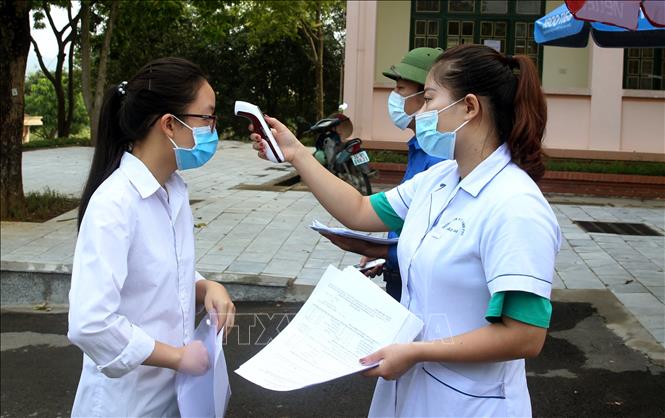 Trong ảnh: Các thí sinh được kiểm tra đo thân nhiệt cùng với giấy xác nhận âm tính với dịch bệnh COVID-19 trước khi vào phòng thi tại điểm thi số 4, thành phố Lào Cai. Ảnh: Quốc Khánh - TTXVN