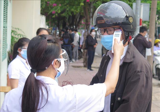 Trong ảnh: Cán bộ y tế kiểm tra thân nhiệt thí sinh dự thi kỳ thi tốt nghiệp THPT năm 2021 trước khi vào điểm thi Nguyễn Văn Trỗi, thành phố Nha Trang, tỉnh Khánh Hòa trong buổi thi đầu tiên. Ảnh: Phan Sáu-TTXVN                               