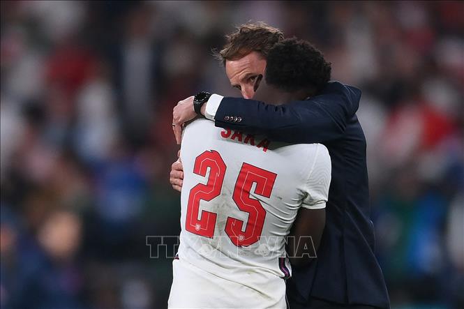 Trong ảnh: Tiền vệ tuyển Anh Bukayo Saka (trái) nhận lời an ủi từ huấn luyện viên Gareth Southgate sau khi thực hiện không thành công quả sút luân lưu quan trọng ở trận chung kết EURO 2020 gặp tuyển Italy, ngày 11/7/2021. Ảnh: AFP/TTXVN