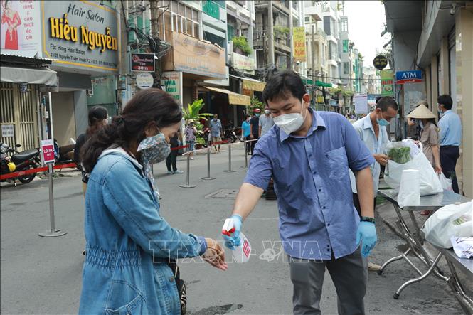 Trong ảnh: Người dân xịt tay sát khuẩn trước khi vào khu vực mua sắm của “Phiên chợ lưu động” được tổ chức tại khu phố 3, phường 2, Quận 3, Thành phố Hồ Chí Minh. Ảnh: Quang Châu - TTXVN

