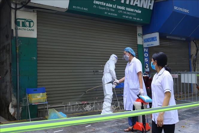 Nhân viên y tế quận Hai Bà Trưng phun khử khuẩn khu vực đầu ngõ 172 Lò Đúc. Ảnh: Hoàng Hiếu - TTXVN 