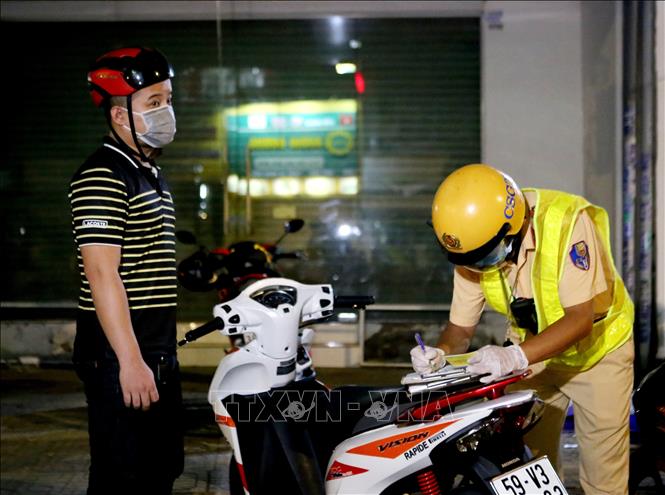 Trong ảnh: Công an lập biên bản xử phạt một trường hợp ra đường không cần thiết sau 18 giờ. Ảnh: Thành Chung - TTXVN