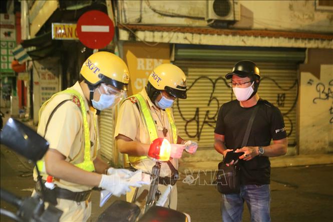 Trong ảnh: Công an lập biên bản xử phạt một trường hợp ra đường không cần thiết sau 18 giờ. Ảnh: Thành Chung - TTXVN