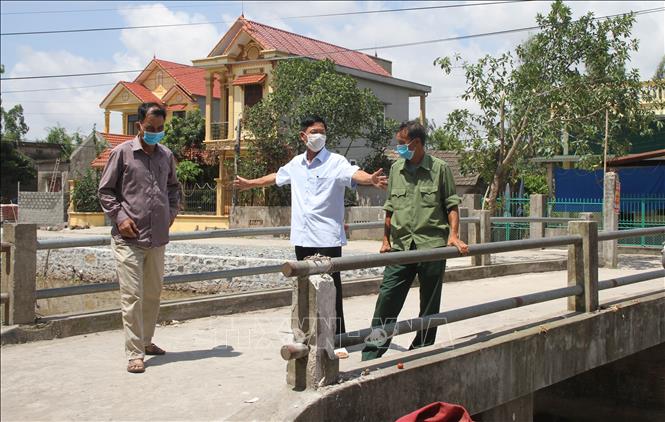 Trong ảnh: Ông Đỗ Quang Sản (giữa) bàn bạc phương án sữa chữa cầu với cán bộ địa phương. Ảnh: Hải Yến-TTXVN.