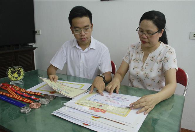 Trong ảnh: Em Vũ Mạnh Tùng cùng mẹ xem lại những thành tích đã đạt được. Ảnh: Thùy Dung - TTXVN