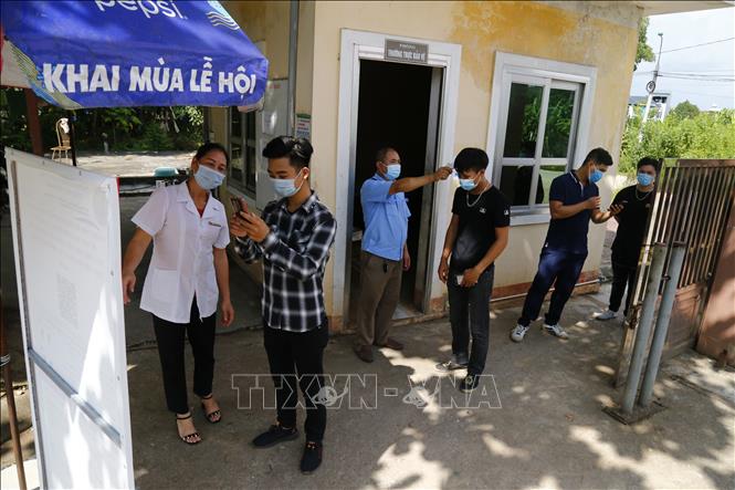 Khai báo y tế và đo thân nhiệt trước khi vào trường. Ảnh: Nam Sương - TTXVN
