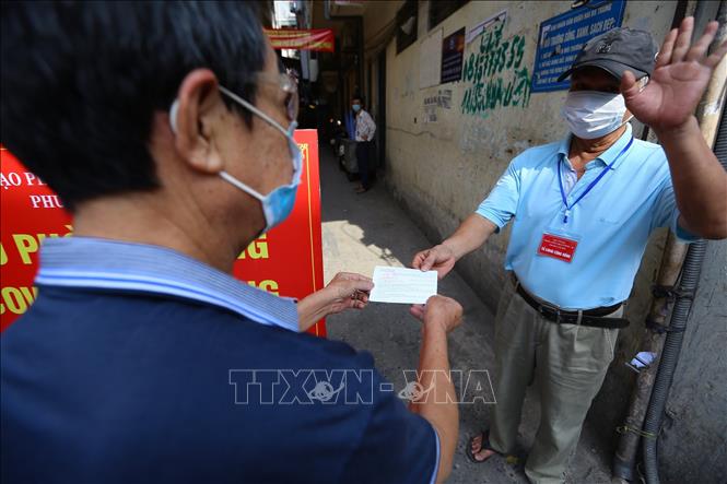 Tổ phòng, chống COVID cộng đồng phường Cầu Dền, quận Hai Bà Trưng kiểm tra thẻ đi chợ của người dân (ảnh chụp sáng 3/8/2021). Ảnh: Hoàng Hiếu - TTXVN 
