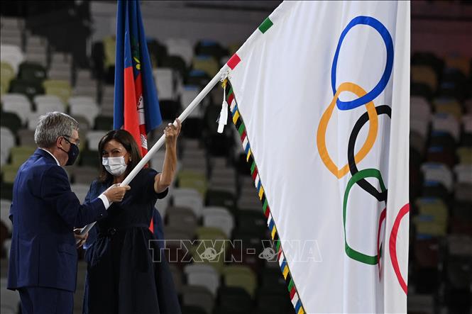 Trong ảnh: Chủ tịch IOC Thomas Bach trao lá cờ Olympic cho bà Ana Maria Hidalgo, Thị trưởng Paris (Pháp) - thành phố đăng cai Olympic mùa Hè 2024, tại lễ bế mạc Olympic Tokyo 2020 trên sân vận động Olympic ở Tokyo, Nhật Bản ngày 8/8/2021. Ảnh: AFP/TTXVN