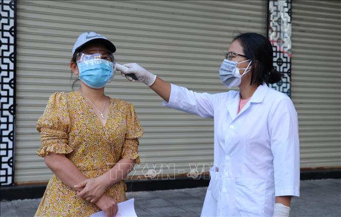 Trong ảnh: Cán bộ y tế đo nhiệt độ cho người là F1 đã hoàn thành cách ly tại nhà. Ảnh: Phạm Cường-TTXVN