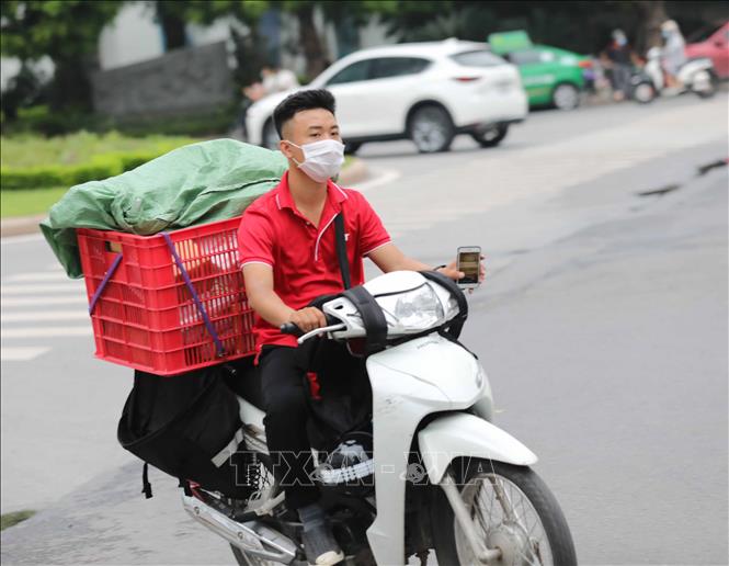 Trong ảnh: Nhân viên giao hàng không đội mũ bảo hiểm khi di chuyển (ảnh chụp chiều 10/8/2021). Ảnh: Thanh Tùng - TTXVN
