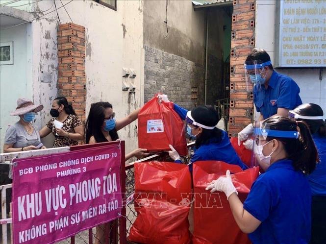 Trong ảnh: Đoàn viên thanh niên Thành phố Hồ Chí Minh cung cấp nhu yếu phẩm cho những hộ dân thuộc khu vực phong toả tại phường 3, Quận 11. Ảnh: Hồng Giang - TTXVN