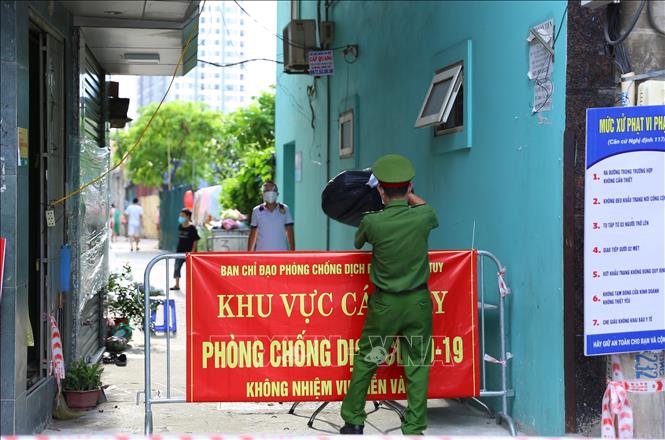 Trong ảnh: Lực lượng công an vận chuyển hàng tiếp tế cho người dân khu vực cách ly. Ảnh: Hoàng Hiếu - TTXVN 