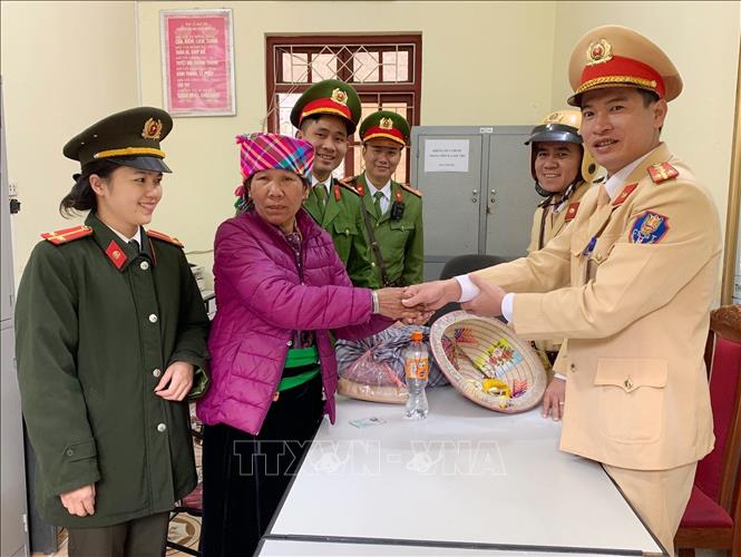 Trong ảnh: Cán bộ, chiến sỹ Công an huyện Mường La, tỉnh Sơn La hỗ trợ nhu yếu phẩm và kinh phí cho bà Đồng Thị Khân (Yên Bái) trở về nhà do bị lạc đường khi đi thăm con.. Ảnh: TTXVN phát.