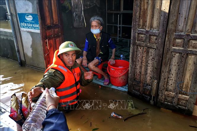 Trong ảnh: Trung uý Hoàng Trung, Công an huyện Lệ Thuỷ (Quảng Bình) lội nước đưa hàng cứu trợ đến mế già. Ảnh: TTXVN