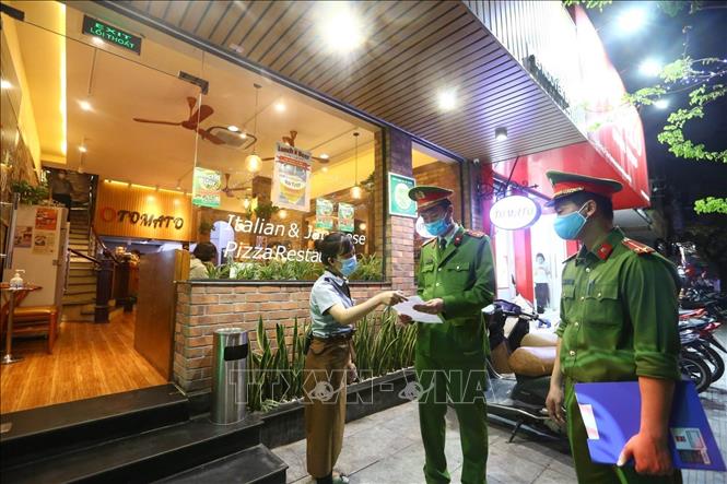 Trong ảnh: Công an phường Nguyễn Du (Hà Nội) tuyên truyền, nhắc nhở các cửa hàng đóng cửa theo quy định phòng chống dịch COVID-19 (26/3/2020). Ảnh: Minh Quyết - TTXVN