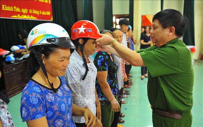 Trong ảnh: Đại tá Vũ Anh Thiều, Phó Giám đốc Công an tỉnh Ninh Bình trao tặng mũ bảo hiểm cho phụ nữ xã Khánh Tiên (huyện Yên Khánh) hưởng ứng ngày gia đình Việt Nam 28/6. Ảnh: Minh Đức - TTXVN
