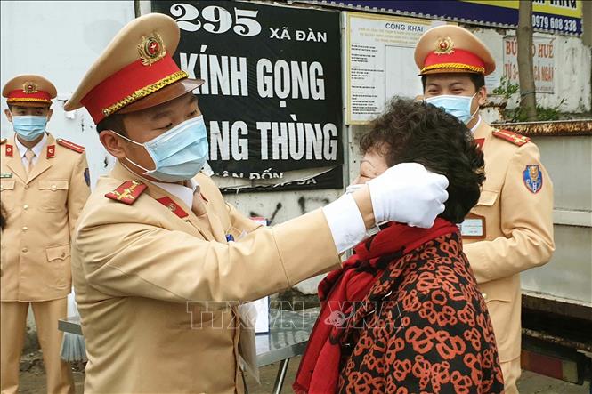 Thực hiện kế hoạch của Công an Thành phố Hà Nội trong đợt cao điểm phòng chống dịch viêm đường hô hấp cấp do chủng mới của virus Corona (nCoV) gây ra, Chi đoàn Thanh niên của Phòng Cảnh sát giao thông, Công an Thành phố Hà Nội phát động phong trào quyên góp tiền mua và phát miễn phí khẩu trang cho người tham gia giao thông, kể cả người đến xử lý vi phạm giao thông tại các đơn vị. Trong ảnh: Cảnh sát giao thông Hà Nội phát khẩu trang miễn phí cho người dân tại phố Xã Đàn. Ảnh: Doãn Tấn - TTXVN

