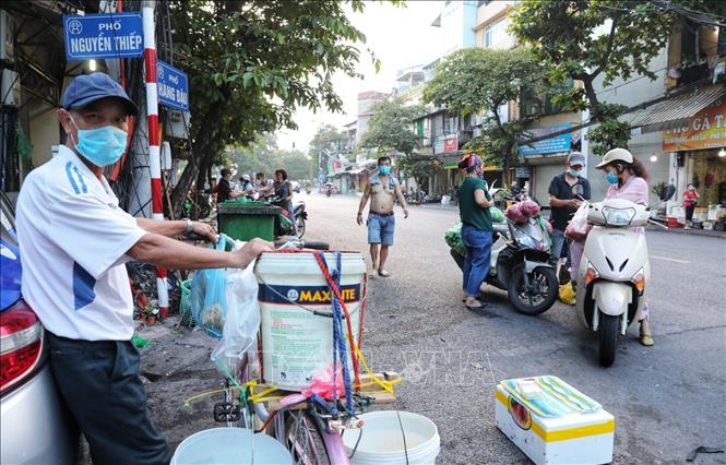 Trong ảnh: Các tiểu thương và người mua tiếp tục di chuyển xuống đoạn ngã ba Hàng Đậu - Nguyễn Thiệp để mua bán sau khi việc họp chợ khu vực bốt Hàng Đậu bị lực lượng chức năng giải tán. Ảnh: Thành Đạt - TTXVN