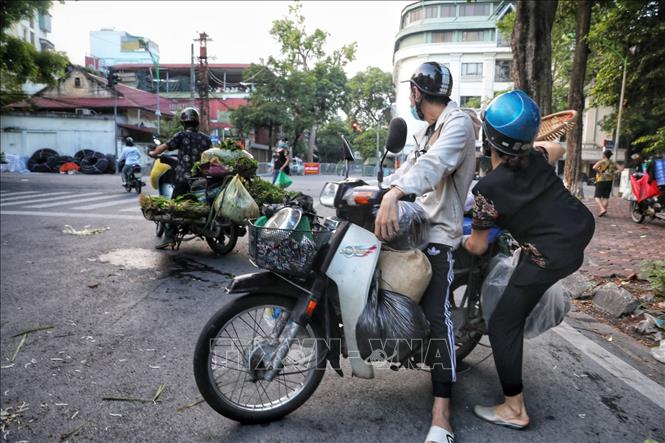 Chỉ khi có lực lượng Công an phường Quán Thánh nhắc nhở và xử lý vi phạm, các tiểu thương và người đi chợ mới vội vàng thu dọn hàng và chạy ra chỗ khác tiếp tục họp chợ. Ảnh: Thành Đạt - TTXVN