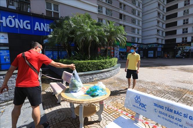 Trong ảnh: Các cư dân tòa nhà CT8C khi nhận hàng hóa đều phải đảm bảo an toàn giãn cách. Ảnh: Tuấn Anh - TTXVN