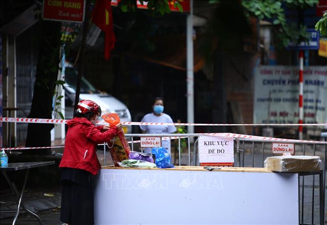 Trong ảnh: Người giao và nhận hàng không chuyển trực tiếp (ảnh chụp sáng 26/8 tại ngõ 24 Kim Đồng). Ảnh: Hoàng Hiếu - TTXVN 
