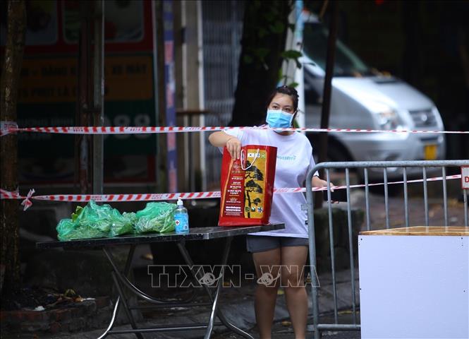 Trong ảnh: Người dân trong khu vực phong tỏa nhận hàng tại rào chắn phong tỏa ngõ 24 Kim Đồng. Ảnh: Hoàng Hiếu - TTXVN 