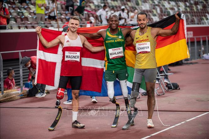 Trong ảnh: VĐV Ntando Mahlangu (giữa) của Nam Phi giành Huy chương Vàng và lập kỷ lục thế giới mới, kỷ lục Paralympic mới ở nội dung nhảy xa nam, hạng T63, tại Paralympic Tokyo 2020, Nhật Bản, ngày 28/8/2021. Ảnh: AFP/TTXVN