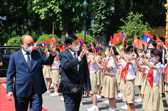 Chủ tịch nước Nguyễn Xuân Phúc và Tổng Bí thư Ban Chấp hành Trung ương Đảng Nhân dân Cách mạng Lào, Chủ tịch nước Cộng hòa Dân chủ Nhân dân Lào Thongloun Sisoulith với thiếu nhi Thủ đô tại lễ đón Đoàn đại biểu cấp cao Đảng và Nhà nước Lào sang thăm hữu nghị chính thức Việt Nam từ ngày 28-29/6/2021. Ảnh: Thống Nhất- TTXVN