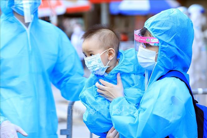 Trong ảnh: Một trẻ nhỏ theo mẹ di chuyển đến khu cách ly. Ảnh: Tuấn Anh - TTXVN
