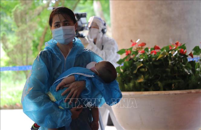 Trong ảnh: Một phụ nữ cùng con nhỏ vừa đáp máy bay xuống sân bay Liên Khương, đang chuẩn bị lên xe trở về khu cách ly. Ảnh: Nguyễn Dũng - TTXVN 