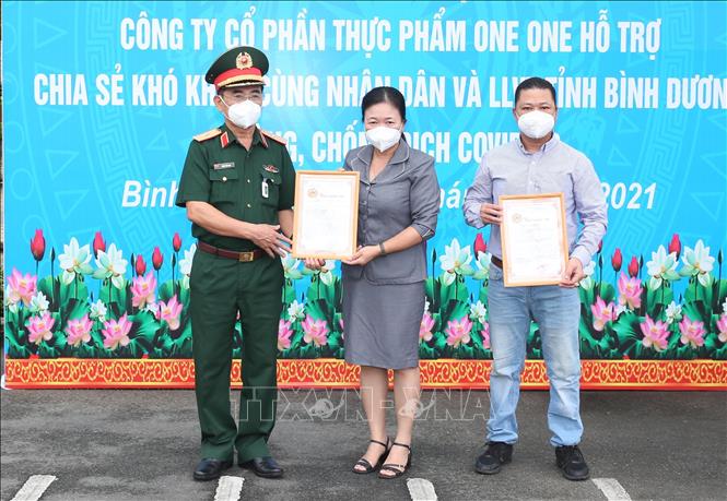 Trong ảnh: Thiếu tướng Trần Văn Sơn và đại diện Nhãn hàng Bánh gạo One One nhận Thư cảm ơn của UBMTTQ VN tỉnh Bình Dương. Ảnh: Hồng Pha - TTXVN phát