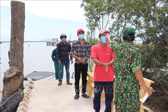 Trong ảnh: Đo thân nhiệt cho ngư dân trước khi lên đất liền ở thị trấn Vàm Láng. Ảnh: Hữu Chí – TTXVN