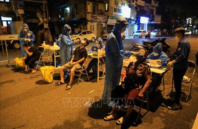 Trong ảnh: Lực lượng Y tế phường Đội Cấn lấy mẫu xét nghiệm xuyên đêm cho người dân ngay trên mặt đường phố Ngọc Hà. Ảnh: Thành Đạt - TTXVN