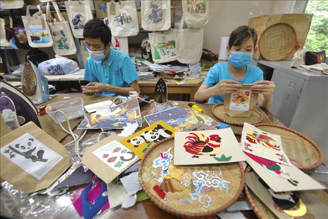 Lấy nguồn nguyên liệu từ vải thừa sau khi cắt may, Vụn Art đã chuyển thể tranh dân gian thành tranh vải. Ảnh: Minh Quyết - TTXVN