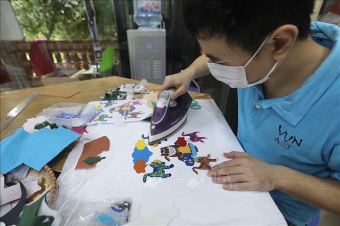 Một sản phẩm mới được sản xuất theo đơn đặt hàng, trang trí trên áo phông bằng các chi tiết theo thiết kế thông điệp 5K của Bộ Y tế dựa trên bức tranh ngũ hổ. Ảnh: Minh Quyết - TTXVN
