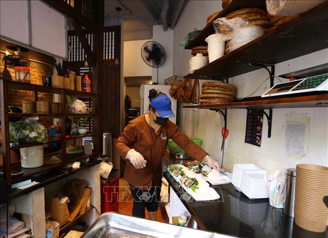 Trong ảnh: Nhân viên cửa hàng ăn tại phường Dịch Vọng Hậu (Cầu Giấy) chuẩn bị đồ để kịp phục vụ khách mua mang về. Ảnh: Hoàng Hiếu - TTXVN 