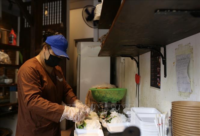 Trong ảnh: Nhân viên một cửa hàng ăn tại phường Dịch Vọng Hậu (Cầu Giấy) chuẩn bị sẵn đồ bán mang về cho khách. Ảnh: Hoàng Hiếu - TTXVN 