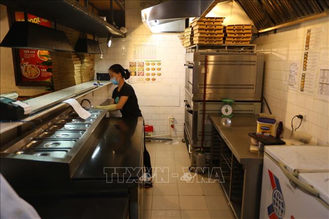 Trong ảnh: Nhân viên một cửa hàng trên phố Trần Thái Tông (Cầu Giấy) lau dọn cửa hàng, chuẩn bị mở cửa trở lại. Ảnh: Hoàng Hiếu - TTXVN 