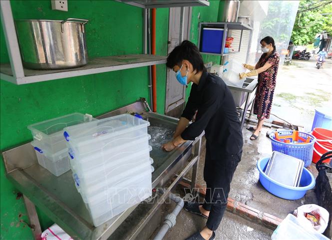 Trong ảnh: Nhân viên một cửa hàng ăn trên phố Duy Tân (Cầu Giấy) lau dọn, chuẩn bị mở cửa trở lại. Ảnh: Hoàng Hiếu - TTXVN 