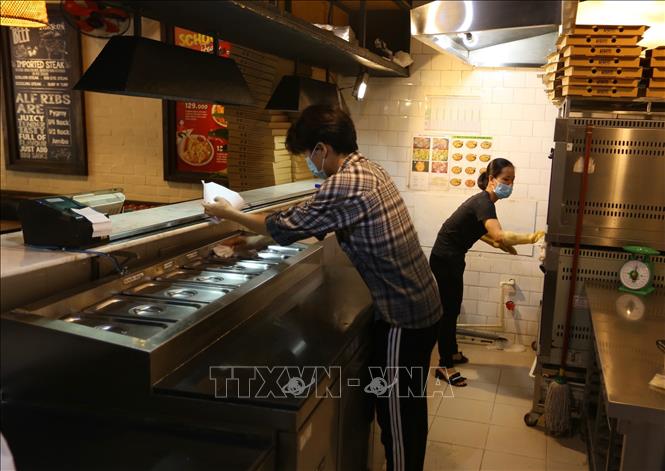 Trong ảnh: Nhân viên một cửa hàng trên phố Trần Thái Tông (Cầu Giấy) lau dọn, chuẩn bị mở cửa trở lại. Ảnh: Hoàng Hiếu - TTXVN 