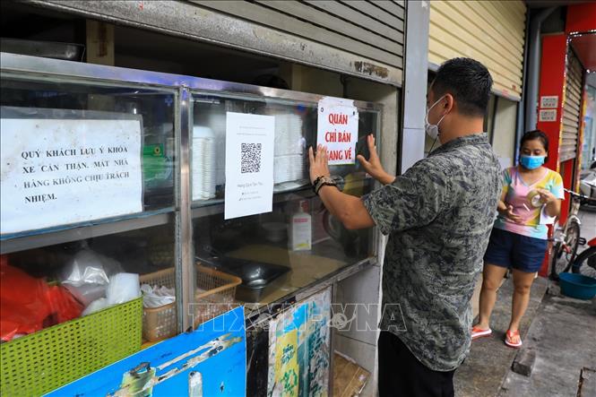 Trong ảnh: Chủ cửa hàng cơm Tâm Thu trên phố Đội Cấn, quận Ba Đình dán mã QR-code để người mua khai báo y tế. Ảnh: Thành Đạt - TTXVN 