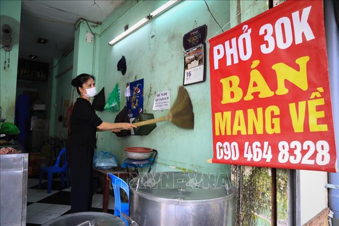 Trong ảnh: Chị Nguyễn Thị Thanh, chủ hàng phở 59 Quán Thánh quét mạng nhện, dọn dẹp cửa hàng trước giờ được mở cửa trở lại. Ảnh: Thành Đạt - TTXVN
