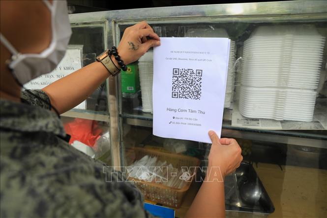 Trong ảnh: Chủ cửa hàng cơm Tâm Thu trên phố Đội Cấn, quận Ba Đình dán mã QR-code để người mua khai báo y tế. Ảnh: Thành Đạt - TTXVN 