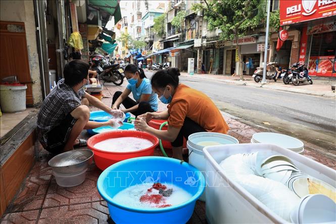 Trong ảnh: Các hàng ăn tại chợ Hòe Nhai, quận Ba Đình rục rịch dọn dẹp rửa chén bát để chuẩn bị mở cửa bán hàng trở lại. Ảnh: Thành Đạt - TTXVN