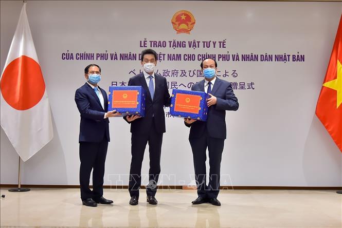 Trong ảnh: Bộ trưởng, Chủ nhiệm Văn phòng Chính phủ Mai Tiến Dũng(phải) và Thứ trưởng Thường trực Bộ Ngoại giao Bùi Thanh Sơn(trái) trao vật tư y tế cho Phó Đại sứ Nhật Bản tại Việt Nam Shinichi Asazuma. Đây là quà tặng của Chính phủ và nhân dân Việt Nam trao tặng Nhật Bản phòng, chống dịch COVID-19. Ảnh: TTXVN phát