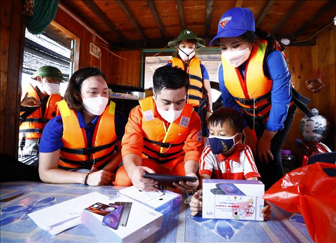 Trong ảnh: Hướng dẫn sử dụng máy tính bảng - quà tặng cho các cháu thiếu nhi tại làng chài xã Văn Đức, huyện Gia Lâm. Ảnh: Minh Đức – TTXVN
