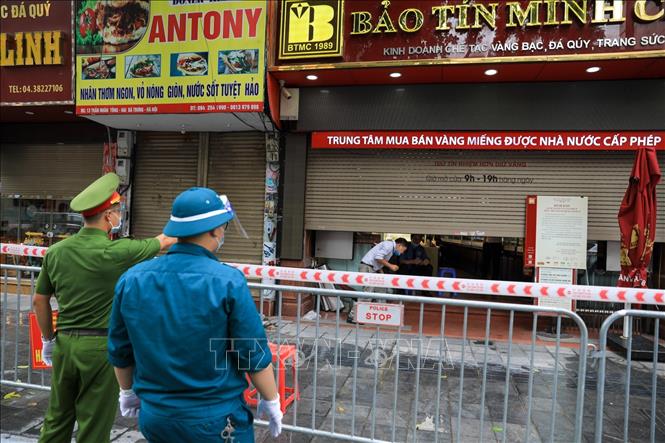 Trong ảnh: Lực lượng chức năng phường Nguyễn Du nhắc nhở cửa hàng kinh doanh Vàng bạc trên phố Trần Nhân Tông đóng cửa do có ca bệnh tại khu vực này. Ảnh: Thành Đạt - TTXVN 