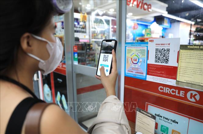 Khách hàng đến siêu thị phải quét mã QR và xịt khử khuẩn trước khi vào mua hàng. Ảnh: Thành Đạt - TTXVN 
